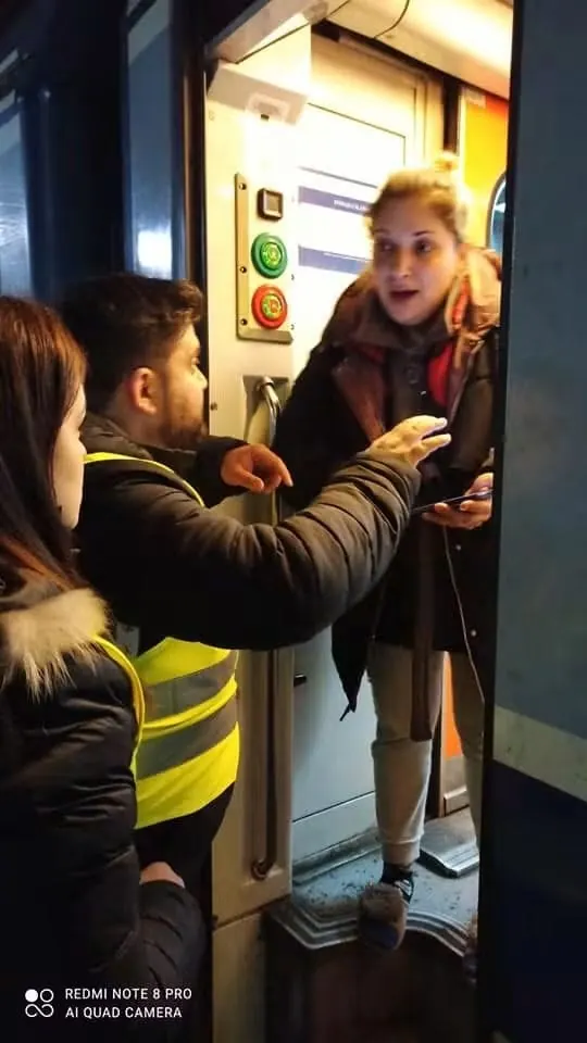 Voluntari oferind îndrumare unei persoane la ușa trenului