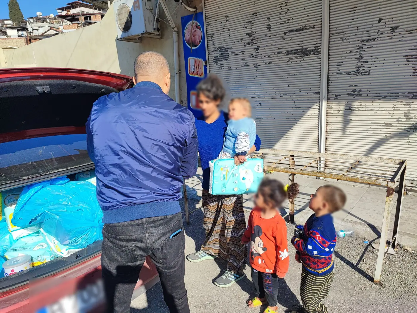 Membru al echipei oferind scutece unei familii, cu fețele ascunse